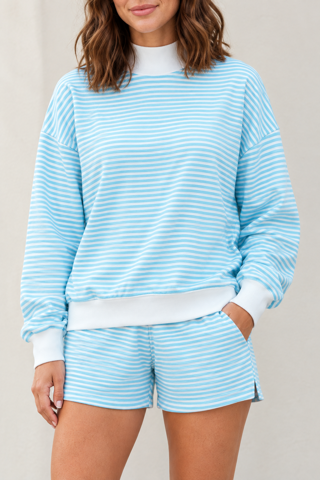 Close-up of sky blue lounge set showing fine horizontal stripes, white ribbed mock neck, cuffs and wide hem band