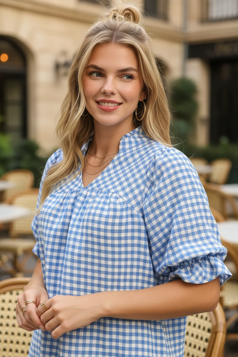 Blue white gingham ruffle sleeve blouse waist-up close-up — V-neck gathered yoke and ruffle elbow sleeve detail blonde model golden light