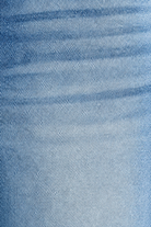 Close-up of medium wash denim showing fabric weave, faded finish and front pocket stitching on barrel jeans