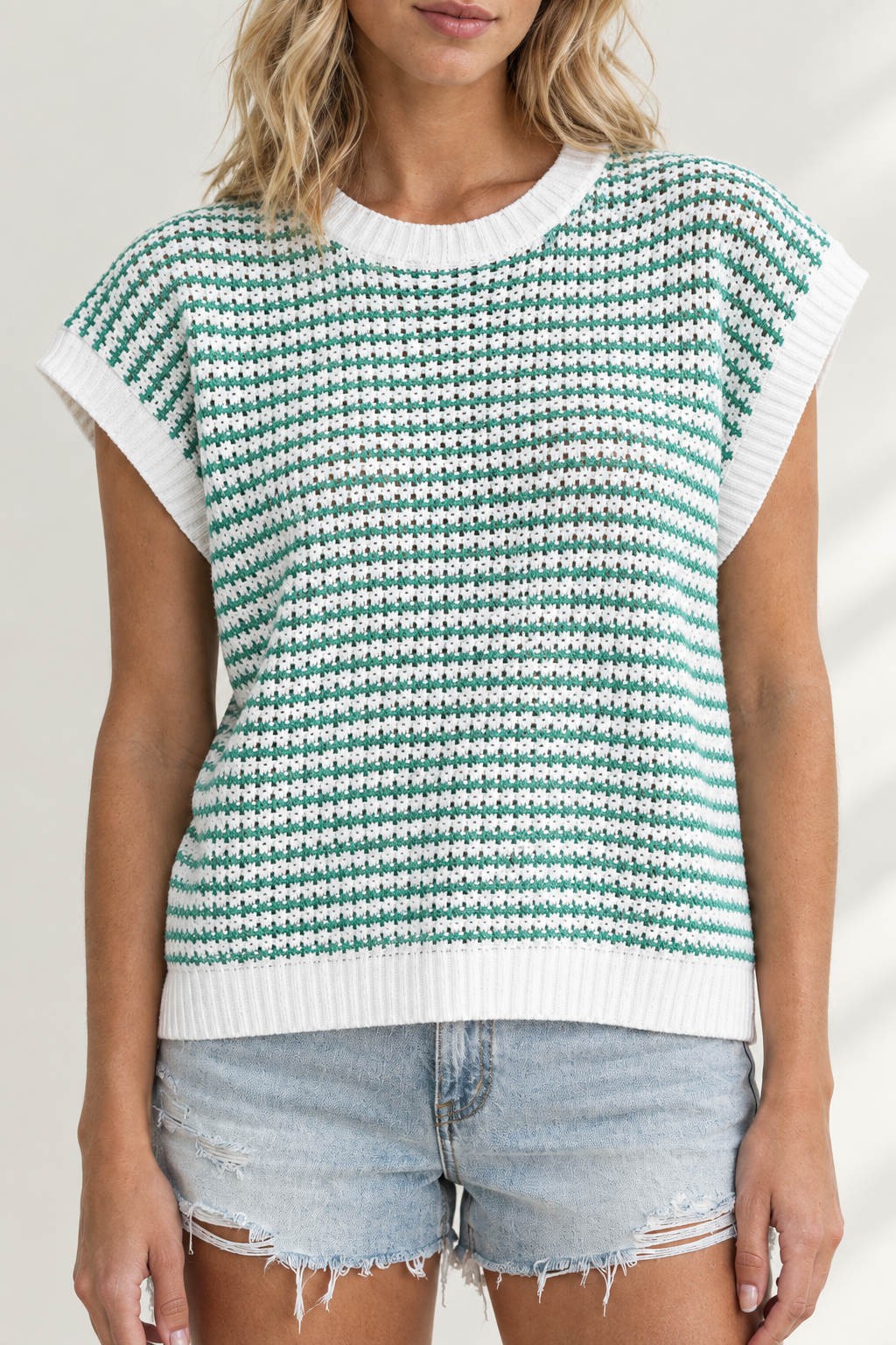 Close-up of green and white striped knit tank showing yarn texture and white ribbed neckline, armholes and hem