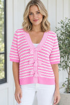 Front view of women's pink and white striped short sleeve knit sweater with V neckline and three bow ties
