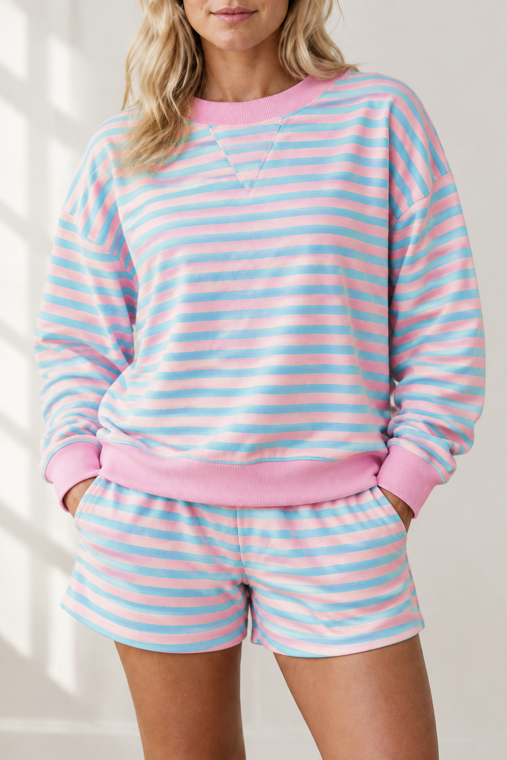 Close-up of pink and aqua striped lounge set showing crew neckline, stitched V detail, pink ribbed cuffs and hem