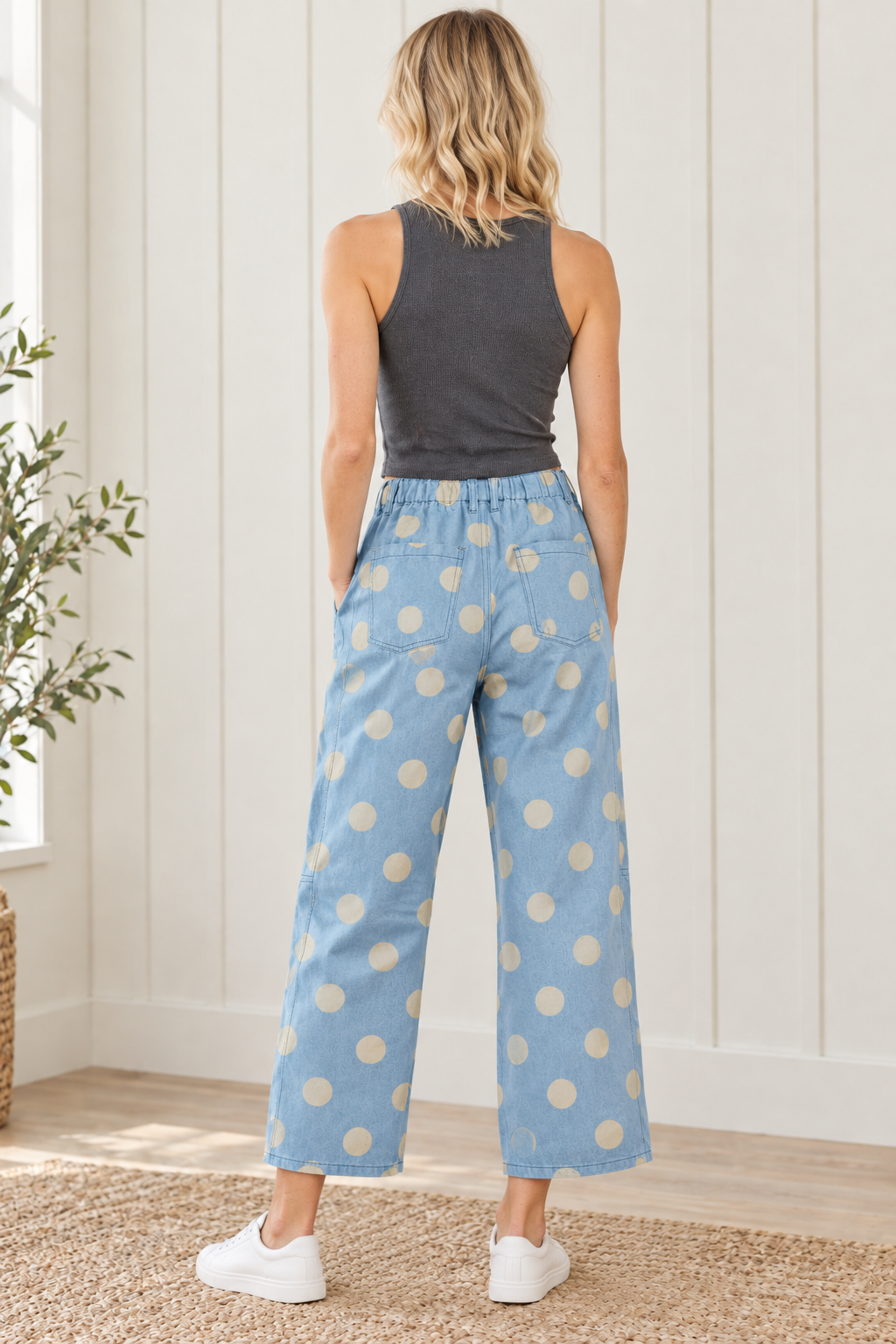 Back view of sky blue jeans with cream polka dots, gathered waistband, patch pockets and cropped hems
