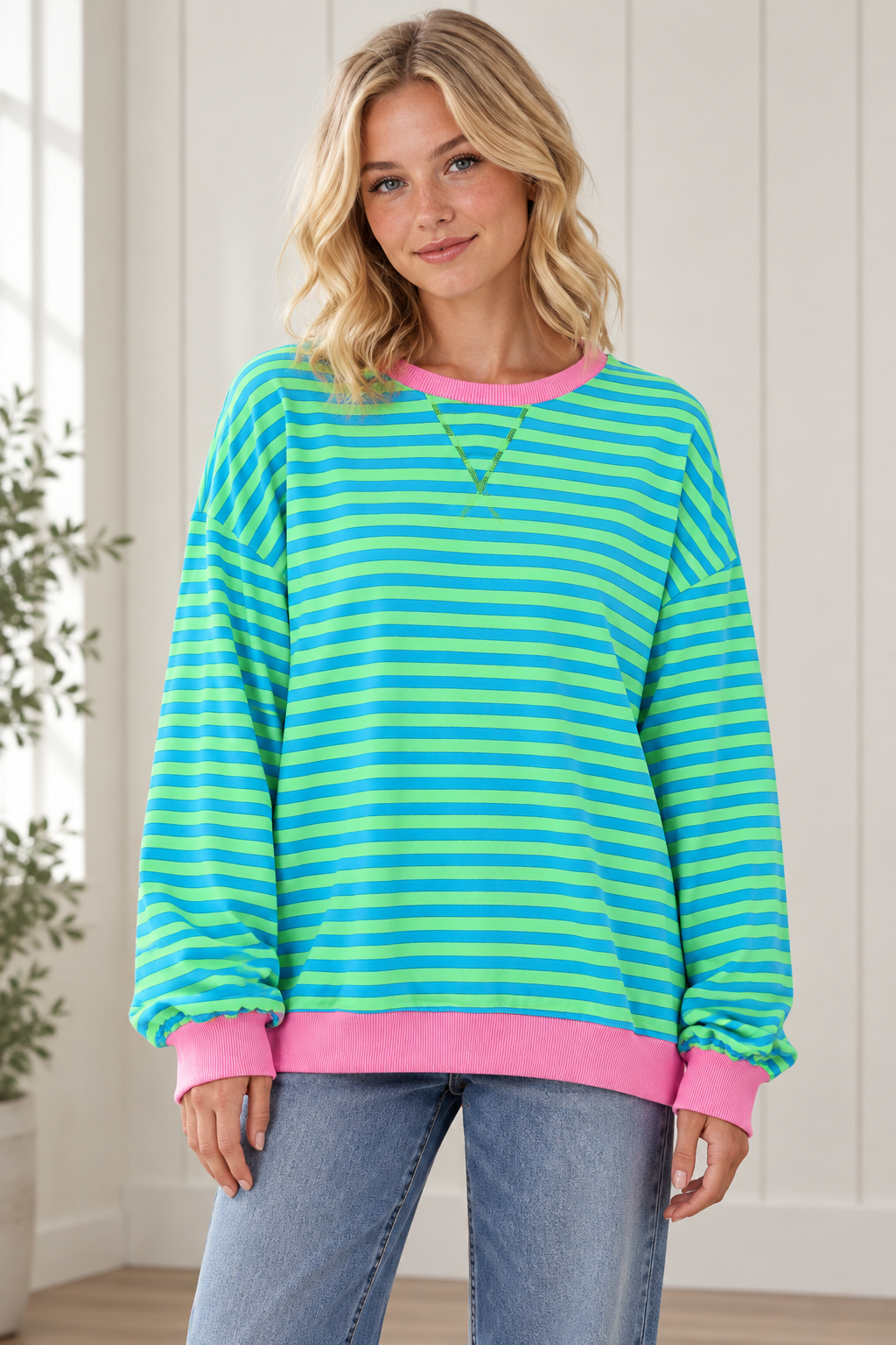 Front view of women's oversized blue and green striped pullover with pink crew neckline, cuffs and hem.