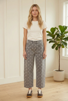 Front styling view of charcoal high waist barrel leg jeans with white polka dots, an ivory tee and retro sneakers.