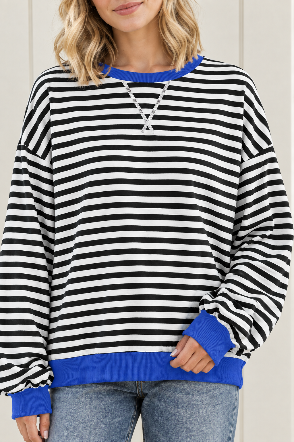 Close-up of striped sweatshirt with blue ribbed crew neckline, white V stitching and contrasting blue cuff.