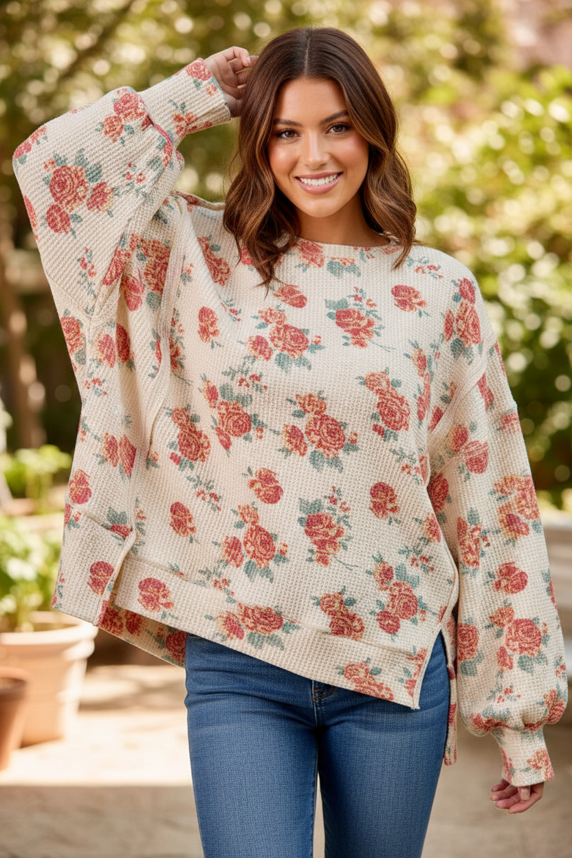 Oversized floral waffle knit sweatshirt upper body front view, one arm raised showing balloon sleeve detail, oatmeal with red and pink rose print