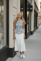 Blue plaid ruffle peplum top candid lifestyle shot — blonde model in white midi skirt, golden hour urban street setting