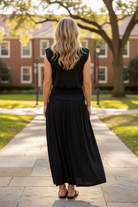 Back view of black modal bubble crop top and flowing ruched waistband maxi skirt set on blonde model, campus courtyard setting, sleeveless two-piece set