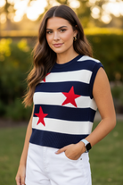 Close-up of navy white stripe sweater vest top with bold red star intarsia knit detail, crew neckline, sleeveless, worn by brunette model, warm golden outdoor light