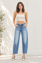 Full-length view of medium wash high rise barrel jeans showing curved legs and ankle-length hems