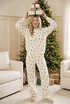 Cream Christmas tree and candy cane crewneck sweatshirt on a smiling model balancing wrapped holiday gifts on her head.