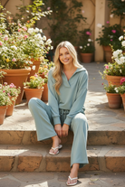 Blue grey scuba two-piece matching set seated outdoor lifestyle photo, oversized open collar pullover and wide leg drawstring pants, relaxed casual coordinated outfit