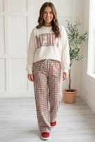 Cream, grey and red plaid drawstring pants in a walking pose showing the relaxed wide legs and full length drape.