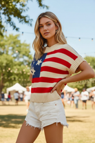 Blonde woman in a cream knit American flag intarsia sweater top with blue star canton and red cream stripes, hands on hips confident pose, three-quarter angle, paired with distressed white denim cutoff shorts