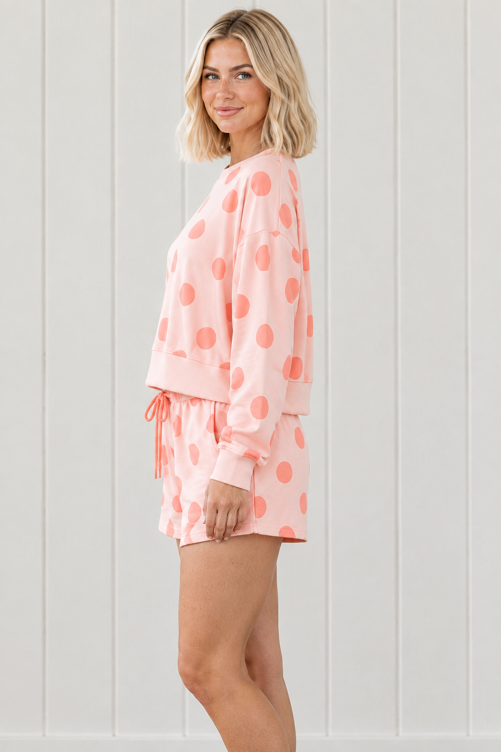 Side view of pink and coral polka dot lounge set with boxy long sleeve pullover and relaxed matching shorts