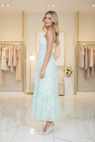 Side profile of mint floral spaghetti strap midi dress with tiered ruffle hem and A-line silhouette, boutique interior background