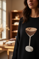 Close-up of espresso martini glass embroidery detail on black crew neck sweater - Thread Bar Boutique
