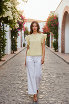 BiBi creamy yellow eyelet ruffle sleeve cotton blouse with scalloped lace hem, styled with white wide-leg linen trousers and strappy heeled sandals, boutique lifestyle fashion at Thread Bar Boutique