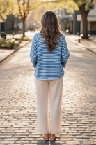 Full body back view of brunette woman in blue stripe boxy half sleeve knit cardigan and cream linen wide-leg pants in outdoor lifestyle setting