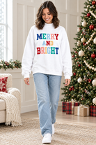 Full-length view of white Merry and Bright holiday pullover paired with light wash jeans and white sneakers