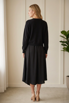 Back view of the Jodifl black two-piece set with long sleeve knit sweater layered over a draped midi dress.