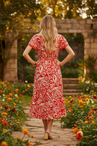 Red and cream paisley midi dress back view showing tiered ruffle hem, flutter sleeve detail, and bold floral print, fully lined lightweight rayon dress