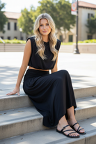 Black sleeveless bubble crop top and flowing ruched waistband maxi skirt, blonde model sitting on concrete campus steps smiling, modal spandex blend two-piece skirt set