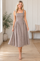 Walking view of brown and cream gingham midi dress showing the flowing pleated skirt