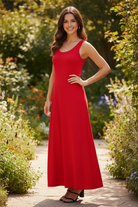Red scoop neck wide strap maxi tank dress three quarter front view — brunette model hand on hip garden setting