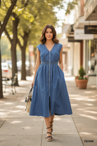 Brunette model walking in Umgee blue chambray denim zip-front midi dress with woven straw tote and wedge sandals, outdoor boutique lifestyle shot