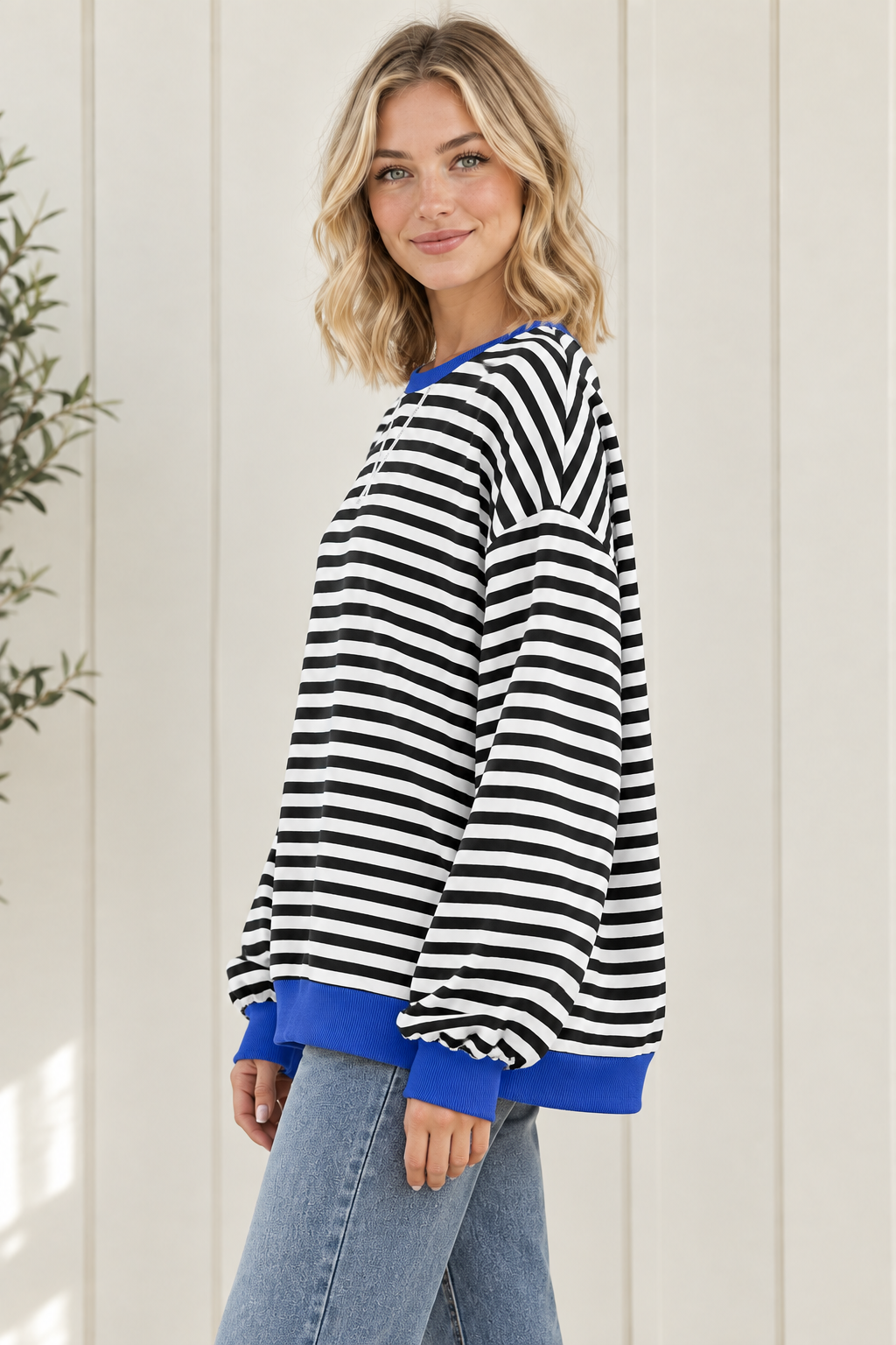 Side view of oversized black and white striped sweatshirt showing relaxed drape, drop shoulders and blue trim.