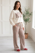 Angled view of Christmas plaid wide leg pants showing the side pocket, elastic waistband and white rope drawstring.