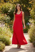 Red wide strap maxi tank dress candid walking — flowing A-line skirt in motion along garden cobblestone path