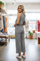 Rear view of blonde model in boutique wearing black white gingham two-piece set showing dramatic crossover ruffle open back detail