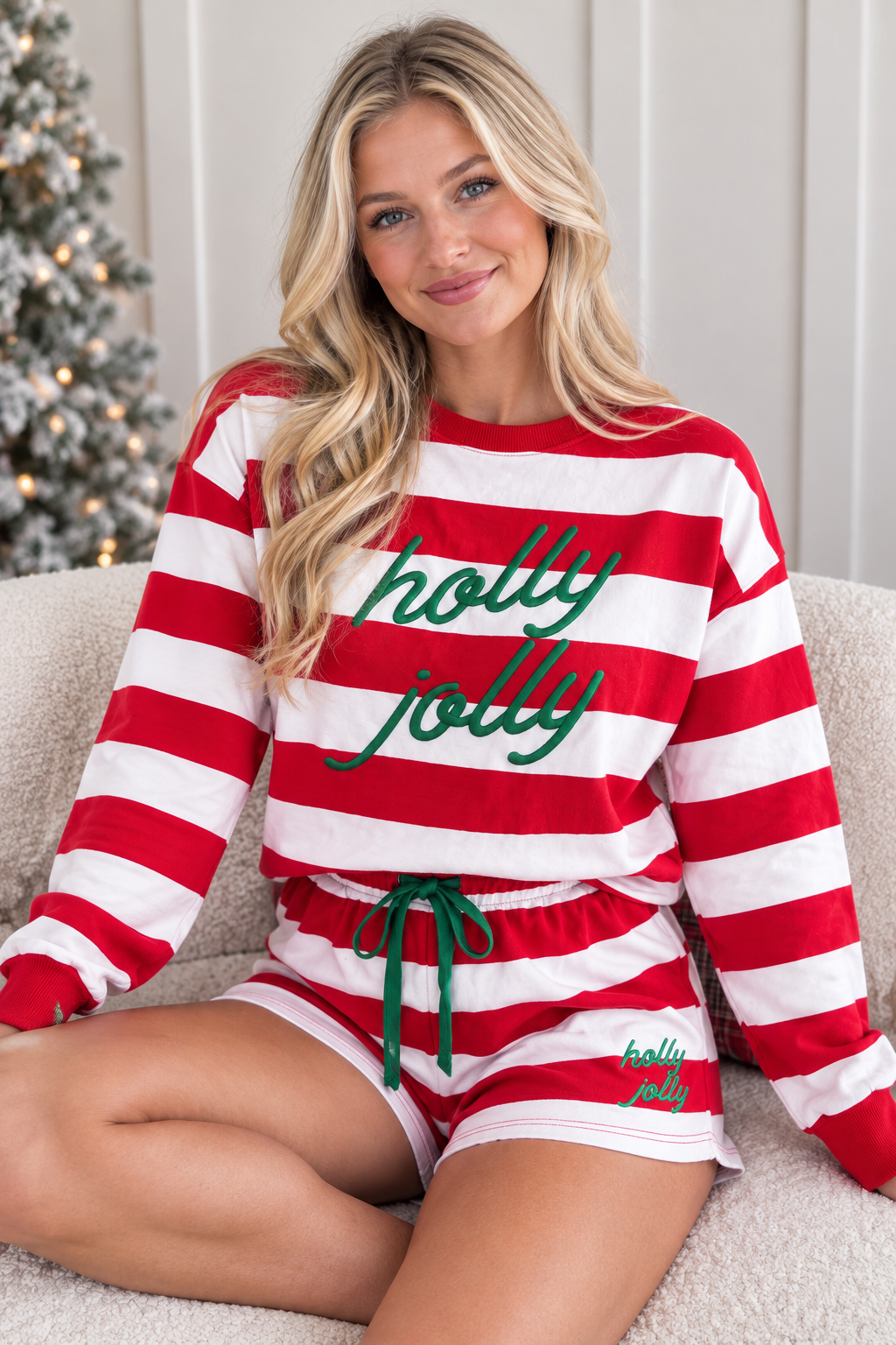 Seated view of red stripe Holly Jolly embroidered pullover and matching shorts set