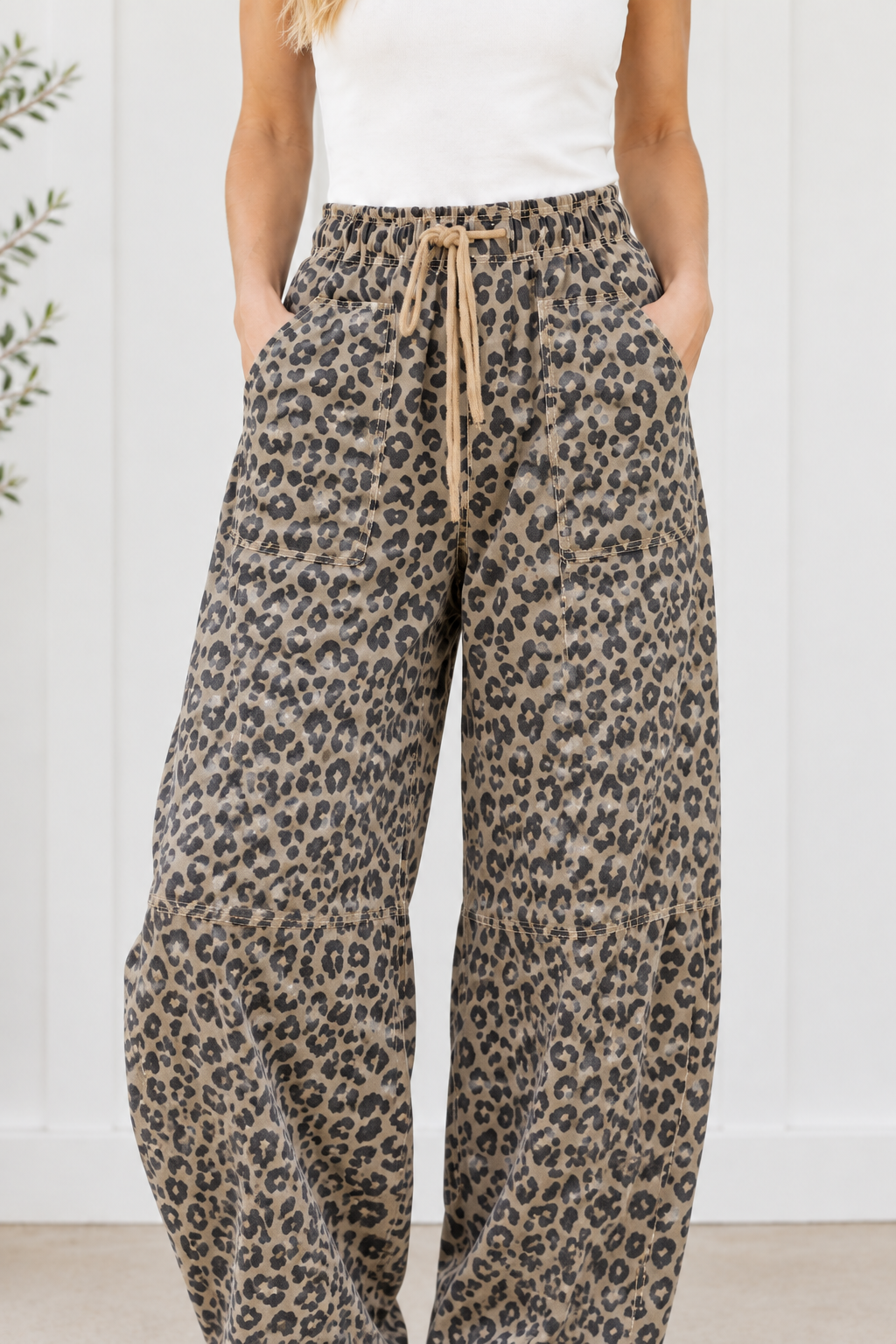 Close-up of leopard print denim pants with gathered elastic waist, tan rope drawstring and stitched front patch pockets