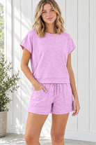 Angled front view of lavender two-piece shorts set showing crew neckline, wide hem band and front patch pockets