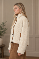 Long sleeve ivory sherpa jacket with mock neckline and brown suede trim from Thread Bar Boutique