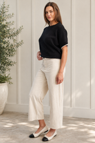 Angled view of beige corduroy pants with a cropped straight-leg silhouette and oversized front patch pockets.