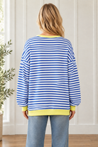 Back view of oversized blue and white striped pullover showing long sleeves and a yellow ribbed hem.