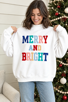White Merry and Bright pullover showing relaxed shape, mock neckline and multicolor stitched holiday lettering