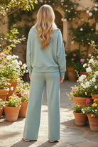 Blue grey scuba two-piece set back view showing wide leg center seam pants silhouette and oversized pullover, relaxed coordinated set outdoor lifestyle