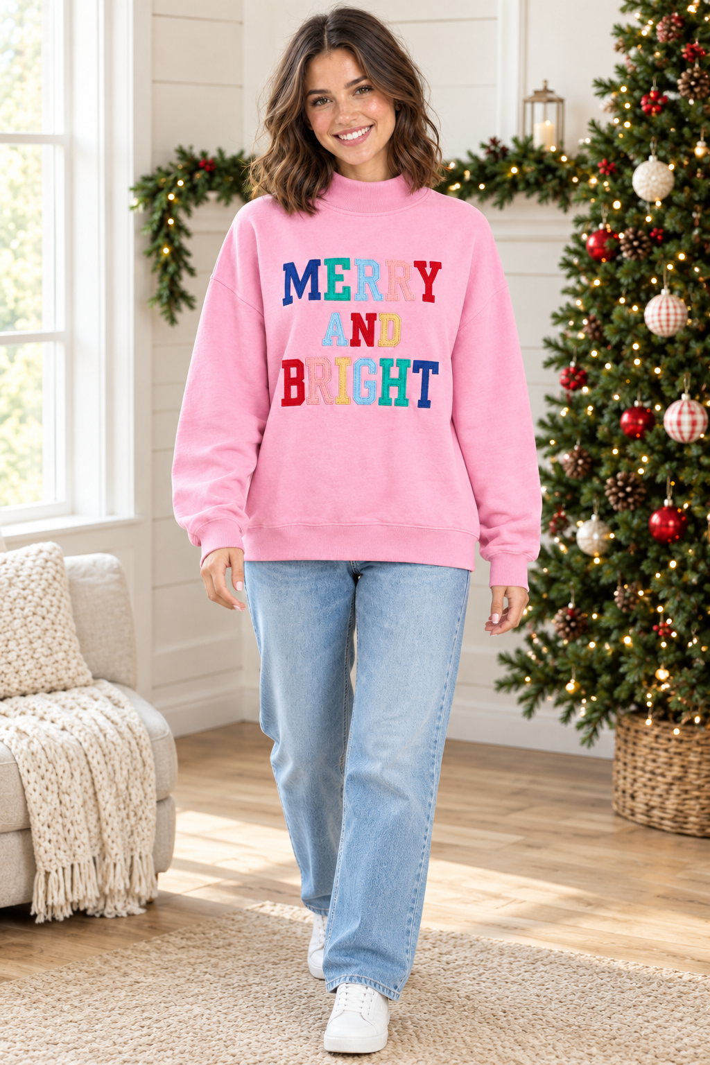 Full-length view of pink Merry and Bright mock neck pullover styled with light wash jeans and white sneakers