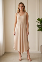 Front view of the Jodifl champagne sleeveless midi dress with front pleat detail and an asymmetrical hem.