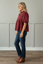 Side profile view of cranberry 100% cotton eyelet puff sleeve blouse showing voluminous short puff sleeves and relaxed babydoll fit