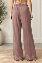 Back view of mauve-brown French terry wide-leg track pants with an elastic waistband and floral eyelash lace hems.