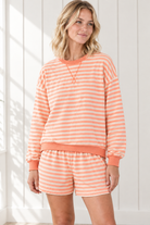 Three-quarter view of orange striped lounge set showing relaxed pullover hem and coordinating pull-on shorts