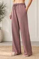 Angled view of mauve-brown French terry track pants showing side pockets, a relaxed wide-leg fit and floral lace hems.