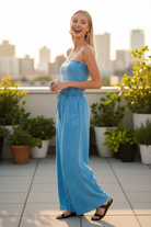 Deep sky acid wash wide-leg jumpsuit three quarter side view — full-length palazzo silhouette blonde model rooftop terrace lifestyle